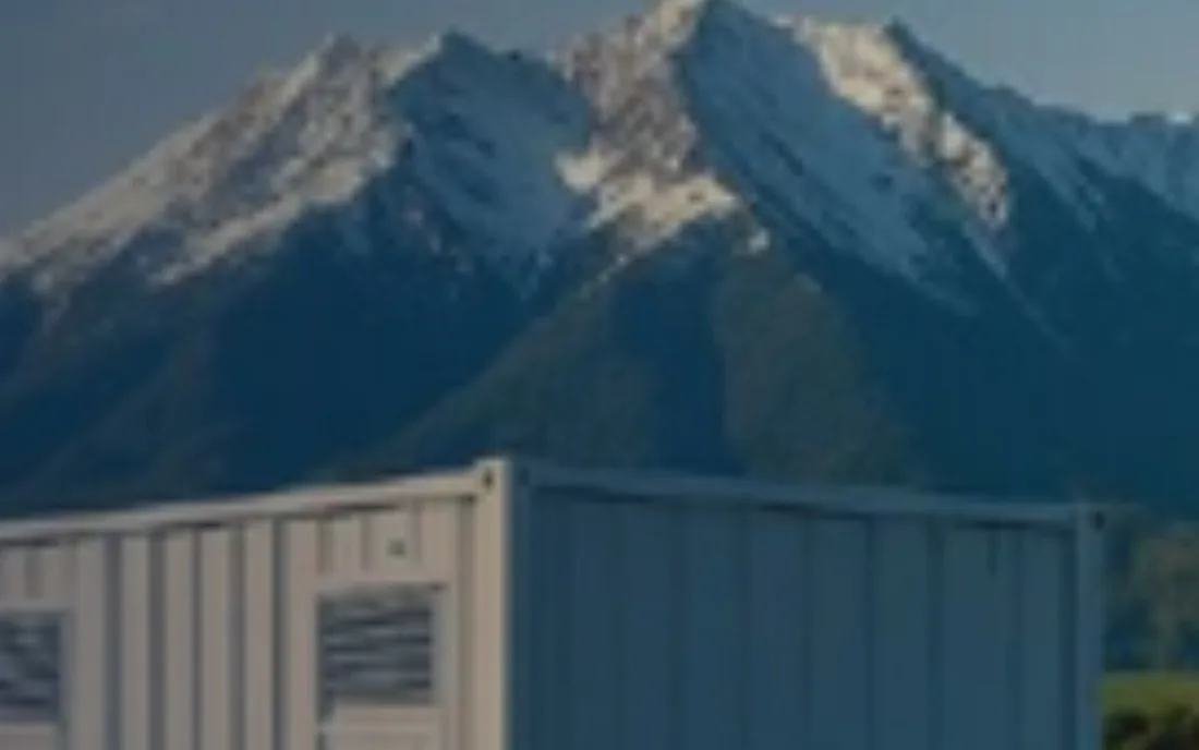A containerized power unit sited below a snow-capped mountain range.